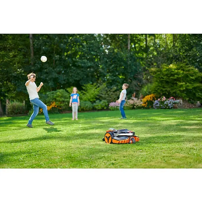 Worx PowerShare 20V Mähroboter Landroid Vision L1300 - 1.300 m², Schnittbreite: 22 cm, Kamera-gestützte Navigation - Ein orangefarbener Rasenmähroboter mäht den Rasen, während eine Familie im Hintergrund Fußball spielt. Praktische Rasenpflege mit dem Mähroboter.