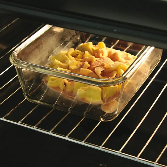 Set de recipientes de almacenaje con tapa hermética - 3 ud., Material: Vidrio - Una fuente de vidrio para hornear con un plato de pasta dentro del horno, la comida es de color amarillo dorado y se ve deliciosa.
