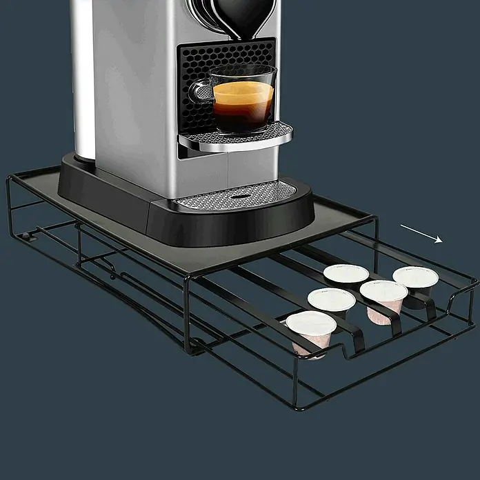 Dispensador cápsulas de café Nespresso - L x An x Al: 31 x 21 x 7 cm, 32 cápsulas - Una cafetera Nespresso se asienta sobre un cajón de cápsulas negro, con cápsulas de café que llenan el cajón.