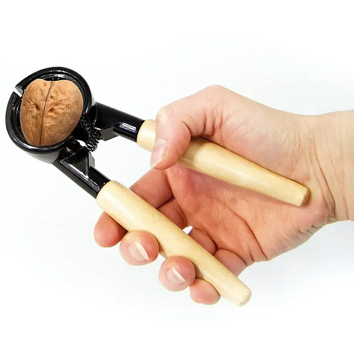 Cascanueces multifuncional - Específico para: Abrir nueces y tapones, Material: Metal - Una mano sujeta un cascanueces de mango de madera, que contiene una nuez lista para ser partida. El cascanueces es negro.