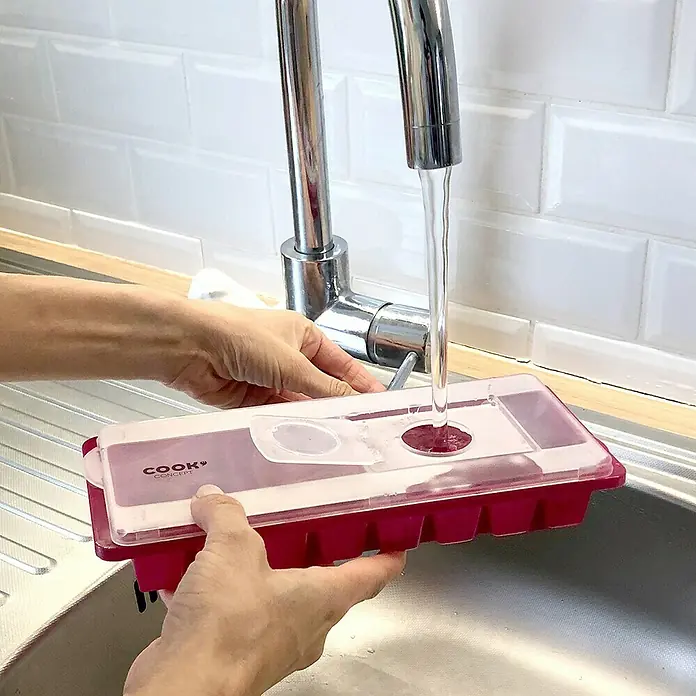 Cubitera con tapa - 26 x 11 cm - Una hielera roja con tapa se llena de agua del grifo, ideal para hacer hielo refrescante para bebidas.