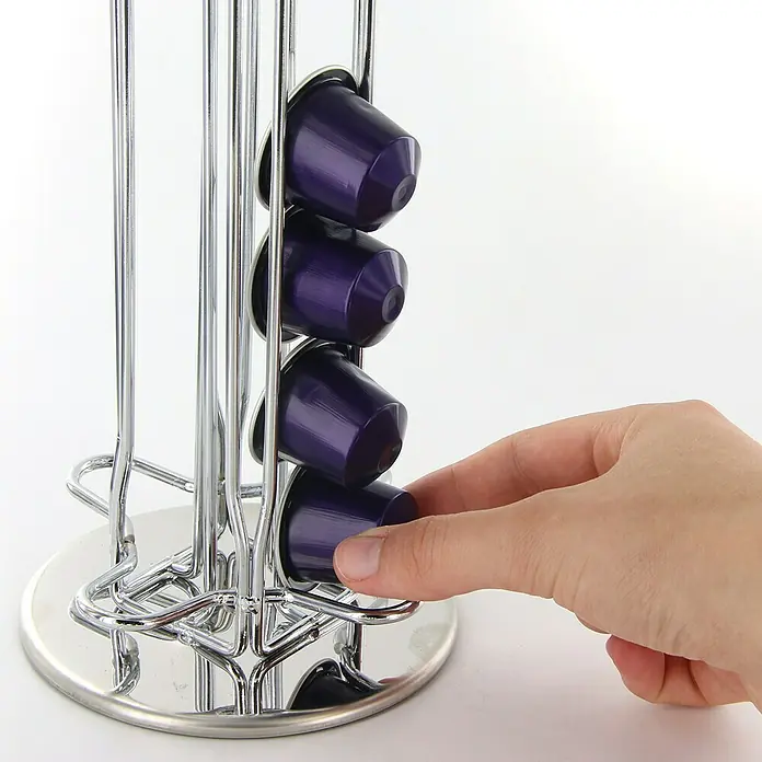 Dispensador de cápsulas de café - Ø x Al: 11,2 x 37 cm, 40 cápsulas - Soporte metálico para cápsulas de café con cápsulas de café moradas y una mano que retira una cápsula.