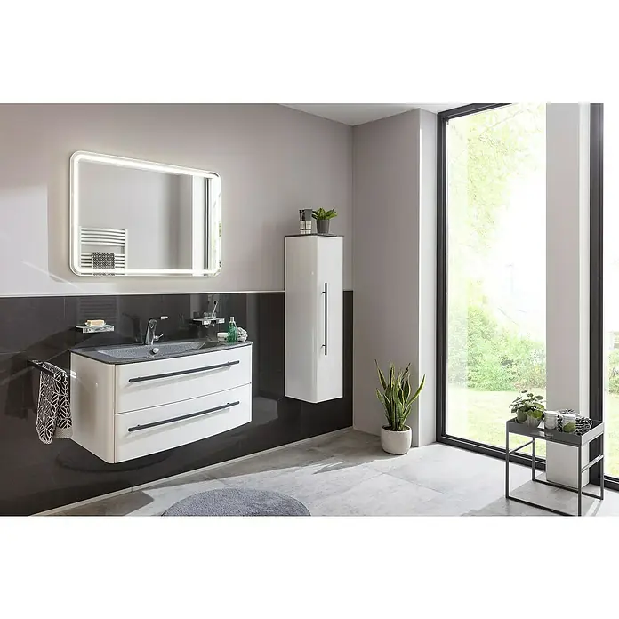Lanzet Classico LED-Lichtspiegel100 x 70 cm - Modernes Badezimmer-Interieur mit beleuchtetem Spiegel, Waschtisch mit Schubladen und Hochschrank in Weiß vor dunklem Fliesenspiegel.