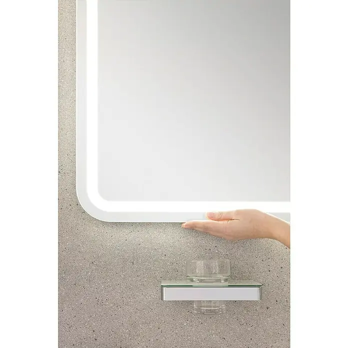 Lanzet Classico LED-Lichtspiegel - 100 x 70 cm - Nahaufnahme eines modernen Spiegels mit Beleuchtung und einer kleinen Glasablage an einer strukturierten Wand.
