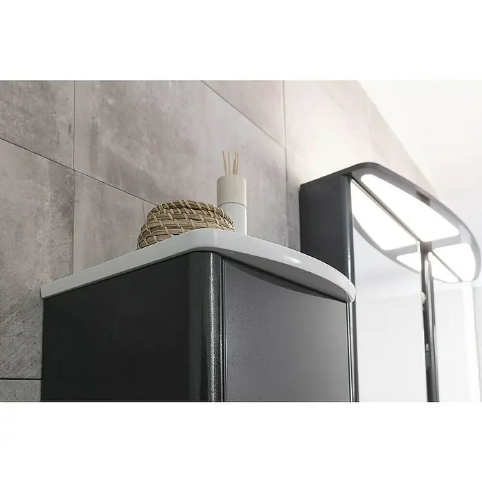 Lanzet Classico Midischrank - B x T x H: 31,2 x 32,5 x 121,4 cm, Weiß, Farbe Griff: Anthrazit, DIN Anschlag: Links - Nahaufnahme eines grauen Badezimmerschranks mit weißer Ablagefläche, darauf ein Korb und ein Duftspender. Spiegel im Hintergrund.