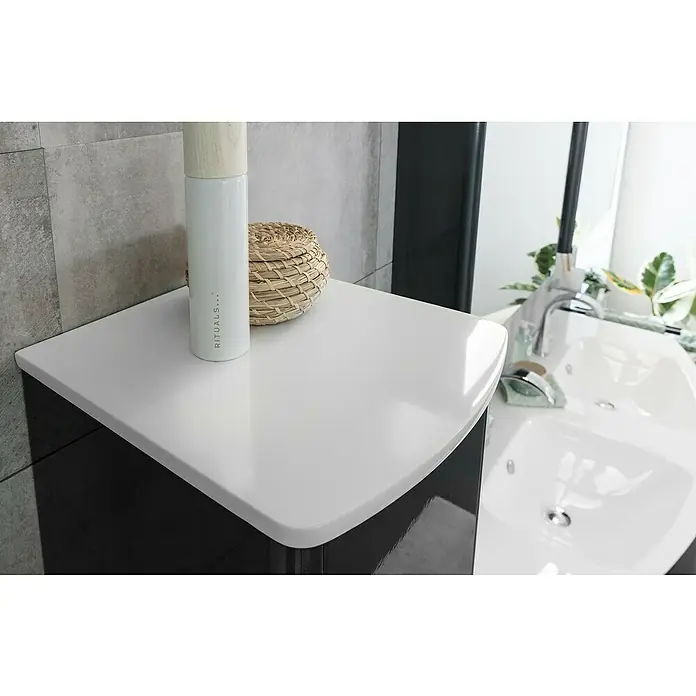 Lanzet Classico Midischrank - B x T x H: 31,2 x 32,5 x 121,4 cm, Weiß, Farbe Griff: Anthrazit, DIN Anschlag: Links - Nahaufnahme einer Badezimmerecke mit einem Rituals-Produkt und einem dekorativen Korb auf einer glänzenden, weißen Oberfläche.