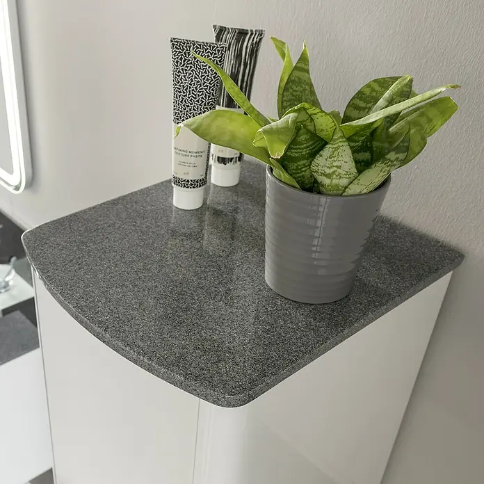 Lanzet Classico Midischrank - B x T x H: 31,2 x 32,5 x 121,4 cm, Weiß/Grau-Metallic, Farbe Griff: Anthrazit, DIN Anschlag: Links - Ein grauer Waschtisch mit einer Zimmerpflanze und zwei Kosmetiktuben, die eine moderne und stilvolle Badezimmeratmosphäre schaffen.