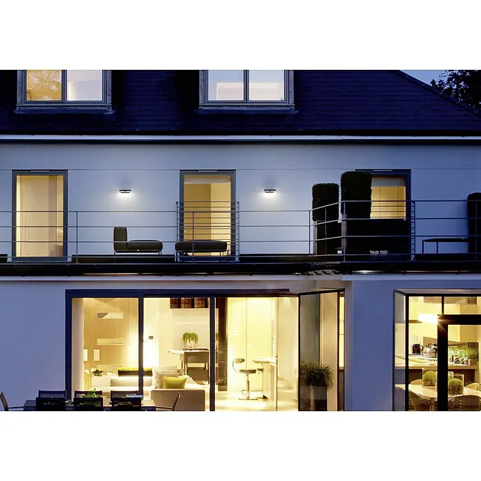 Ledvance LED-Außenwandleuchte Endura Style Mini Spot - 13 W, 100 x 230 x 54 mm, Grau, IP44 - Ein modernes zweistöckiges Gebäude mit Außenbeleuchtung, die die Architektur hervorhebt und für eine warme Atmosphäre sorgt.