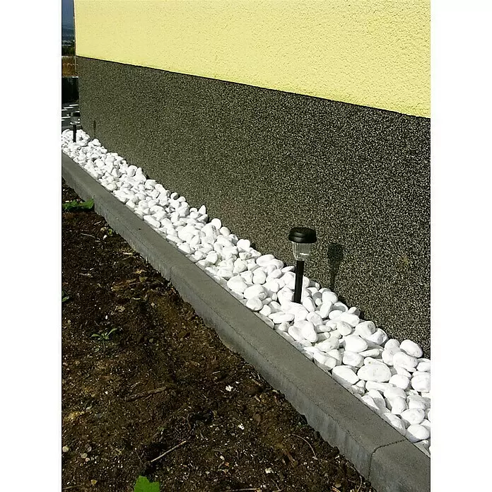 EHL Tiefbordstein - 100 x 30 x 8 cm, Grau - Weiße Ziersteine und eine graue Betonumrandung säumen die Gebäudefassade, ergänzt durch Solarleuchten.