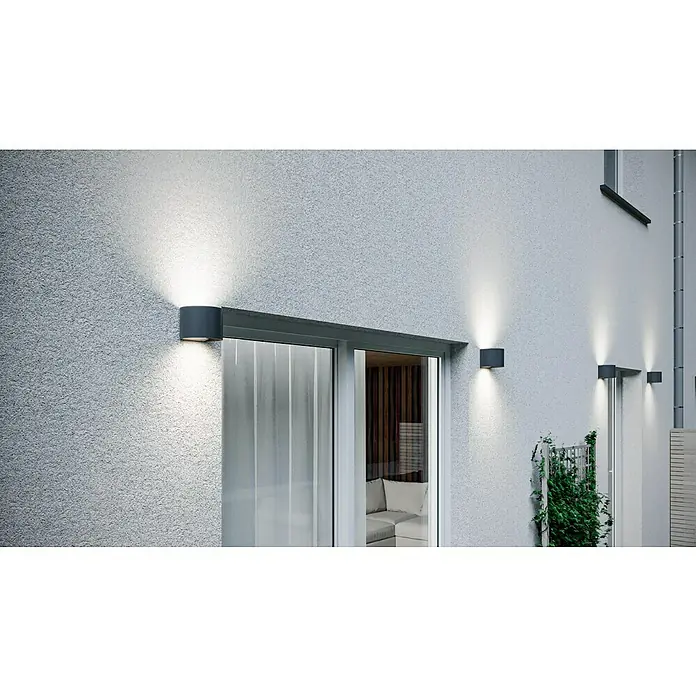 Starlux LED-Außenwandleuchte Umea - 8 W, 11,6 x 13,6 x 10 cm, Anthrazit, IP54 - Drei moderne, graue Wandleuchten beleuchten die Fassade eines Hauses und setzen architektonische Details gekonnt in Szene.
