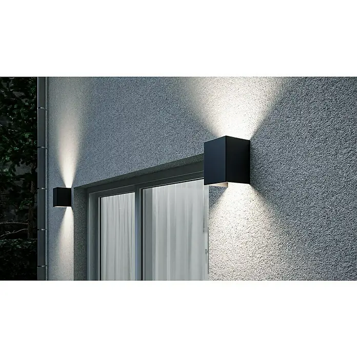 Starlux LED-Außenwandleuchte Umea XXL - 9 W, 12 x 12 x 16 cm, Anthrazit, IP54 - Nahaufnahme von zwei würfelförmigen Wandleuchten, die ein helles, gerichtetes Licht an einer strukturierten Fassade ausstrahlen.