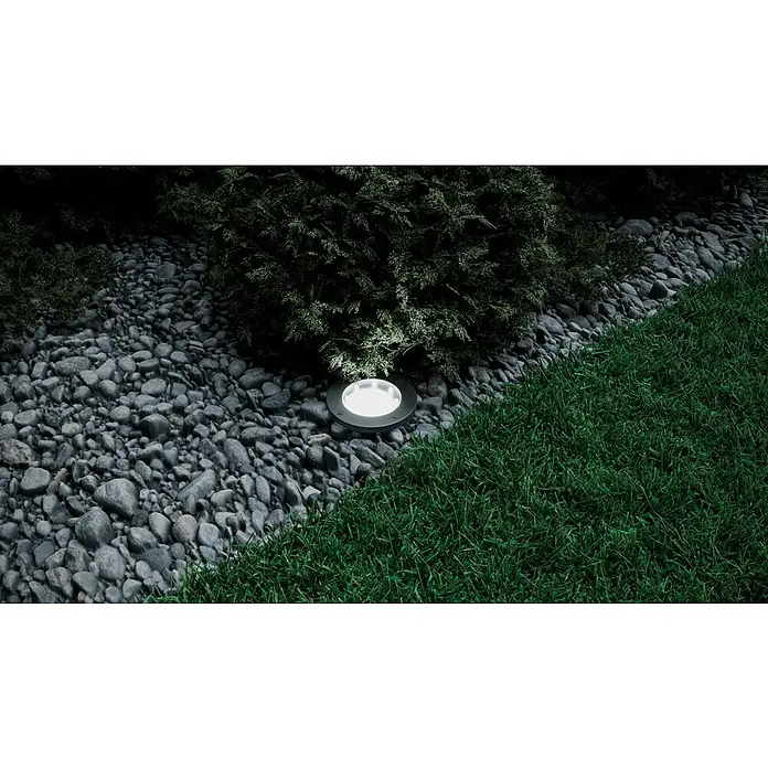 BAUHAUS Solarleuchten-Set Neue Generation - 0,1 W, Schwarz, IP44, 3 lm - Bodeneinbaustrahler beleuchtet einen Gartenweg, umgeben von Kies, Gras und Sträuchern. Die Leuchte setzt einen hellen Akzent in der dunklen Umgebung.