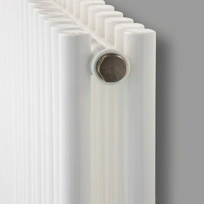 Ximax Raumheizkörper Gamba Duplex - B x H: 470 x 1.800 mm, Wärmeleistung bei Vorlauftemperatur von 75 °C (D: 50): 1.291 W - Nahaufnahme eines weißen Heizkörpers mit vertikalen Rohren und einem silberfarbenen Anschlussstück an einer grauen Wand.