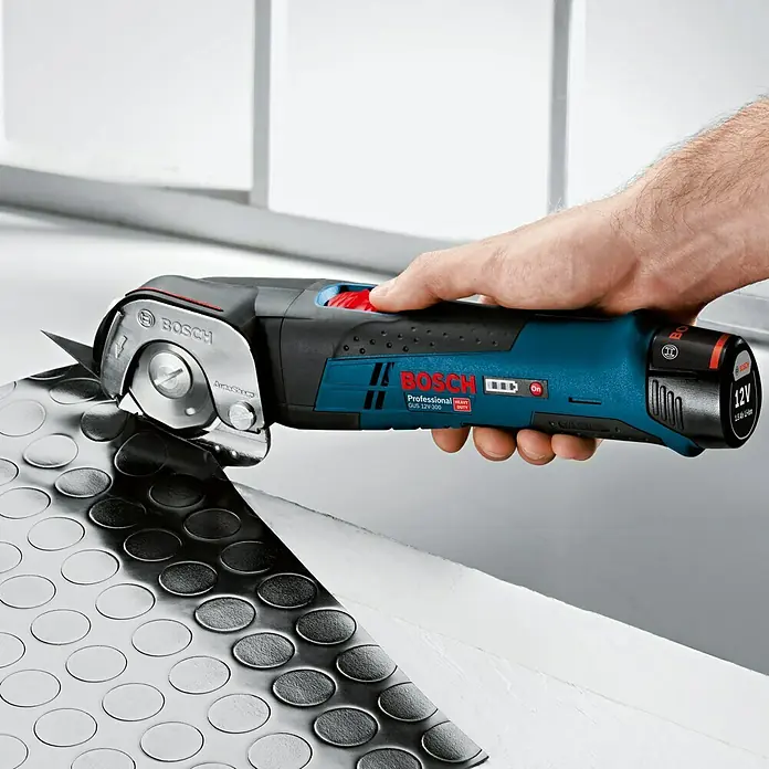Bosch Professional Akku-Universalschere GUS 12V-300 - 12 V, Li-Ionen, Ohne Akku, Geeignet für: Materialien bis 11 mm Stärke - Nahaufnahme einer Bosch GUS 12V-300 Akku-Universalschere in Aktion, die ein schwarzes, kreisförmiges Muster schneidet.