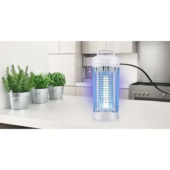 Farolillo antimosquitos LED - 12 W, Blanco - Matamoscas junto a vegetación en una encimera de cocina.