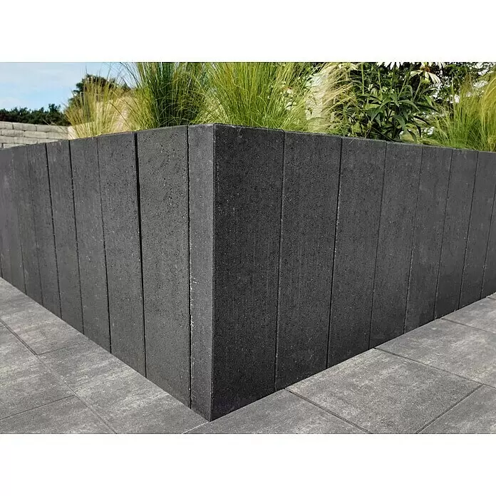 Diephaus Rechteckpalisade Mini - Anthrazit, 8 x 20 x 90 cm, Beton - Dunkelgraue Betonsteine bilden ein Hochbeet mit Pflanzen, das graue Pflastersteine begrenzt.