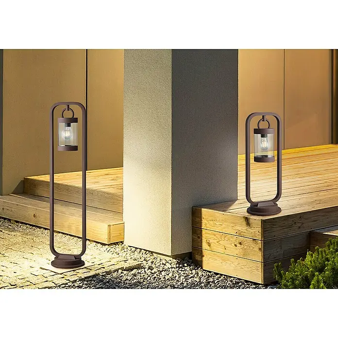 Trio Lighting Sobremuro exterior Sambesi - 28 W, Color del marco: Óxido, 21 x 23 x 60 cm, Sin bombillas - Dos elegantes luces exteriores con un diseño moderno iluminan una zona de entrada con una terraza de madera y un camino de grava.