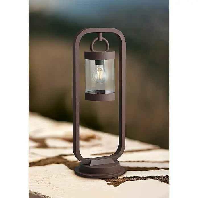 Trio Lighting Sobremuro exterior Sambesi - 28 W, Color del marco: Óxido, 21 x 23 x 60 cm, Sin bombillas - Primer plano de una linterna decorativa para exteriores con bombilla y marco metálico marrón, creando un ambiente acogedor.