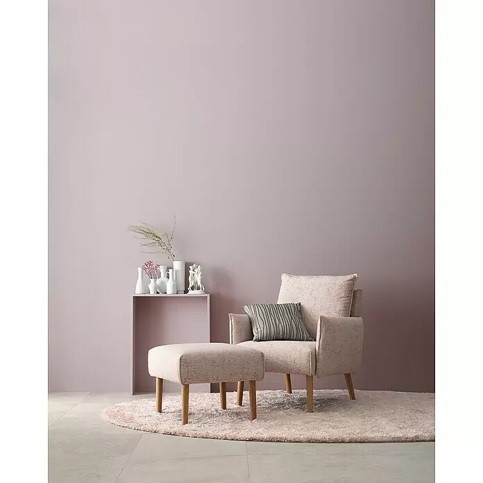 SCHÖNER WOHNEN-Farbe Wandfarbe Designfarbe - Elegantes Puderlila, Matt, 1 l, Konservierungsmittelfrei - Sessel und passende Ottomane aus rosa Stoff mit Holzbeinen, in einer sanften Einrichtung.