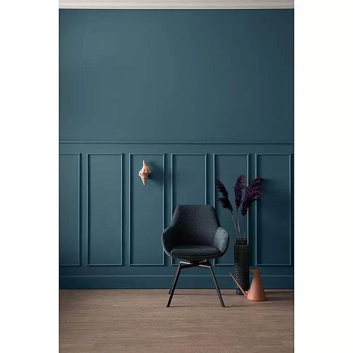 SCHÖNER WOHNEN-Farbe Wandfarbe Designfarbe - Charmantes Petrolblau, Matt, 2,5 l, Konservierungsmittelfrei - Moderner dunkelgrauer Stoff-Sessel mit schwarzen Beinen in stilvollem Raum mit blauer Wandverkleidung.