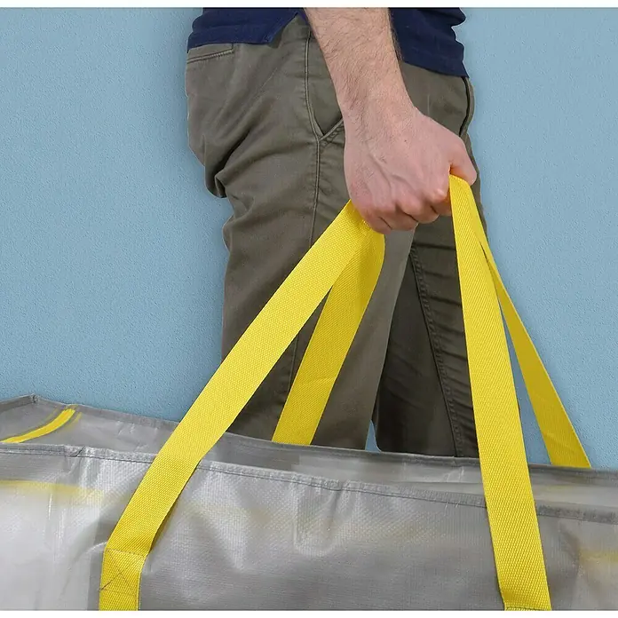 Aufbewahrungstasche TaurusL x B x H: 45 x 90 x 45 cm, 180 l, Kunststoff - Nahaufnahme einer Person, die eine große Umzugstasche mit gelben Trägern hält und so die Robustheit und den Komfort hervorhebt.