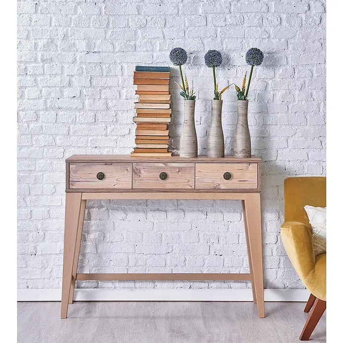 Nesu Pomo para muebles Cuero Viejo - Ø x Al: 35 x 16 mm, Cuero envejecido, 1 ud. - Una consola estrecha de madera clara con tres cajones, decorada con libros y jarrones de flores contra una pared de ladrillo.