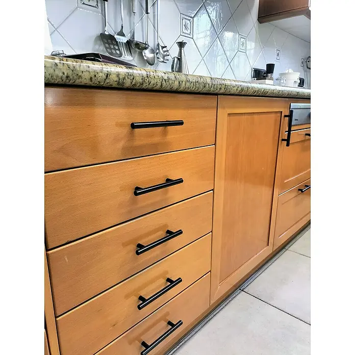 Nesu Tirador para muebles - Largo: 242 mm, Distancia entre orificios: 192 mm - Primer plano de gabinetes de madera con elegantes tiradores de barra negros que realzan la estética moderna de la cocina.