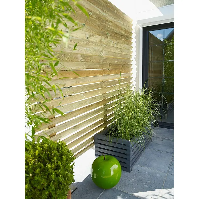 Cerland Tarima para terraza Diego - L x An x Es: 240 x 9,6 x 1,9 cm, Pino - Escena de jardín con valla de madera, jardinera y decoración de manzana verde. La valla de madera aporta privacidad y estructura.