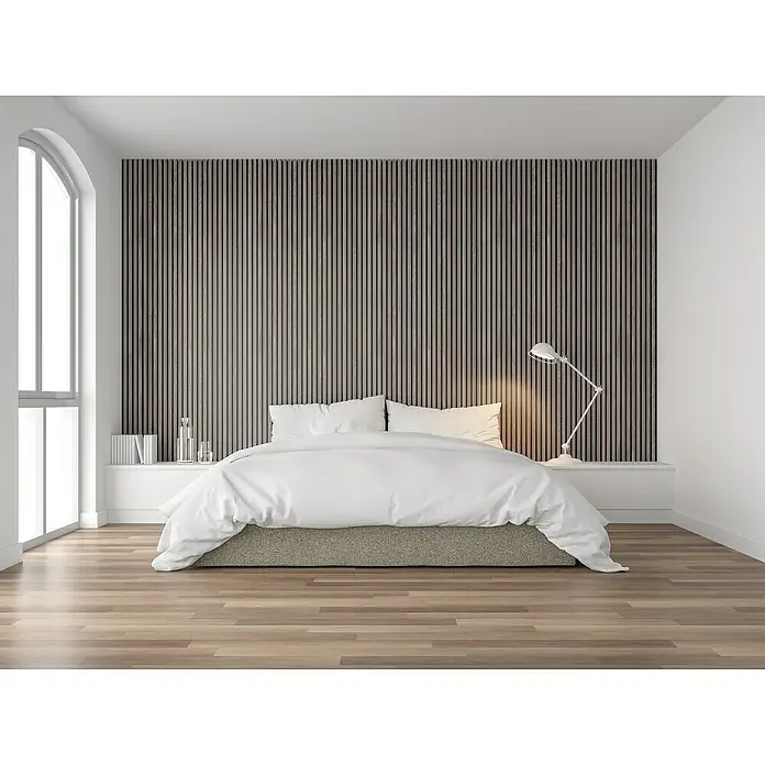FibroTech Akustikpaneel Proff - Grey Oak, L x B x S: 3.000 x 605 x 22 mm - Ein stilvolles Schlafzimmer mit einem großen Bett und einer Akzentwand aus Holzlatten. Die Einrichtung ist modern und einladend gestaltet.