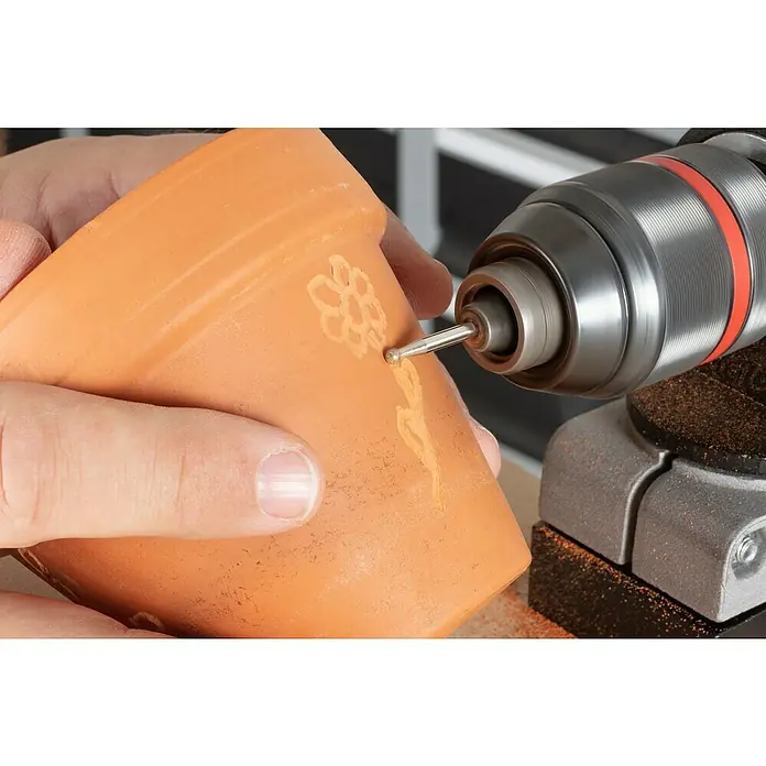 Wolfcraft Fresa de diamante - Diámetro: 3 mm - 5 mm, Diámetro vástago: 3 mm, 3 pzs. - Primer plano de una persona que usa un Dremel para decorar una maceta, mostrando el proceso de grabado.