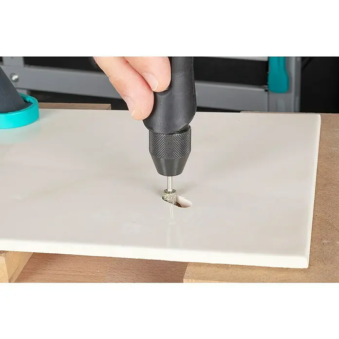 Wolfcraft Fresa de diamante - Diámetro: 3 mm - 8 mm, Diámetro vástago: 3 mm, 2 pzs. - Una toma cercana de un hombre haciendo un agujero en una baldosa con una multiherramienta.