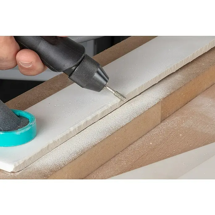 Wolfcraft Fresa de diamante - Diámetro: 4 mm - 5,5 mm, Diámetro vástago: 3 mm, 3 pzs. - Primer plano de una herramienta de pulido trabajando sobre una superficie blanca, rodeada de polvo de madera.