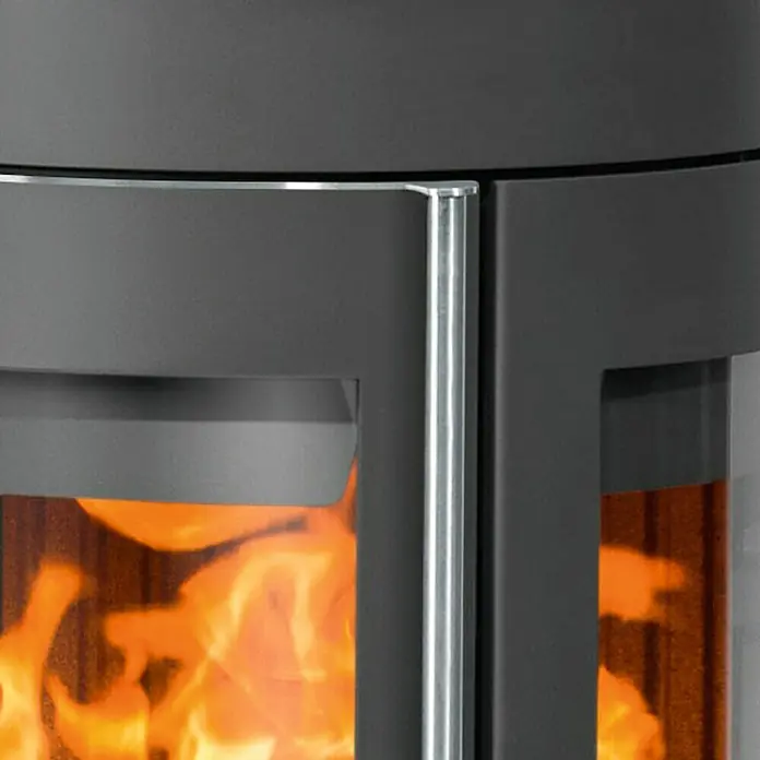 Justus Kaminofen Mino Trios 2.0 - 5,5 kW, Raumheizvermögen: 88 m³, Farbe Verkleidung: Grappa, Schwarz - Nahaufnahme eines Kaminofens mit sichtbarem Feuer, der eine warme und gemütliche Atmosphäre erzeugt.