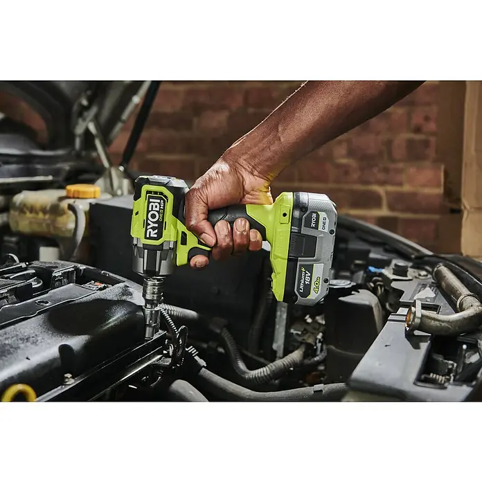Ryobi ONE+HP Akku-Schlagschrauber RIW18C-0 - 18 V, Ohne Akku, 450 Nm - Nahaufnahme eines Ryobi ONE+ Akku-Schlagschraubers, der an einem Automotor verwendet wird. Das Werkzeug ist grün und grau, mit einem 18V Akku.