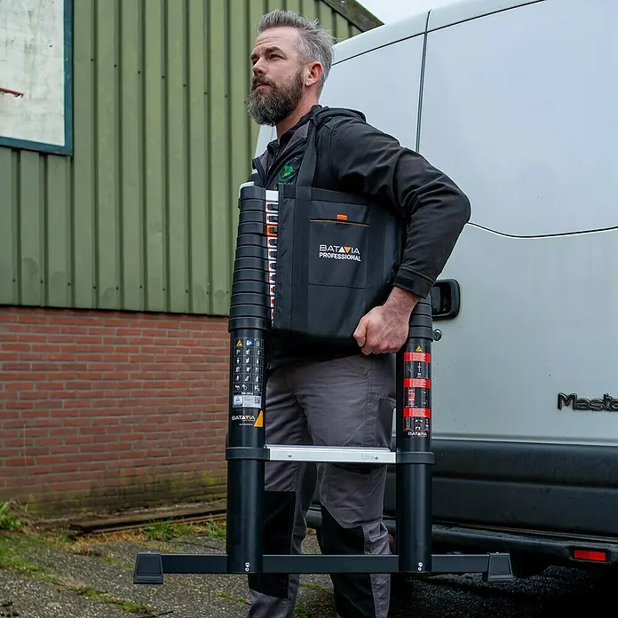 Batavia Teleskopleiter Professional - B x H: 88 x 9 cm, Anzahl Tritte: 12 Stk., Arbeitshöhe: 4,6 m - Mann trägt eine zusammenklappbare Teleskopleiter von Batavia Professional mit Tragetasche. Ideal für Profis und Heimwerker.