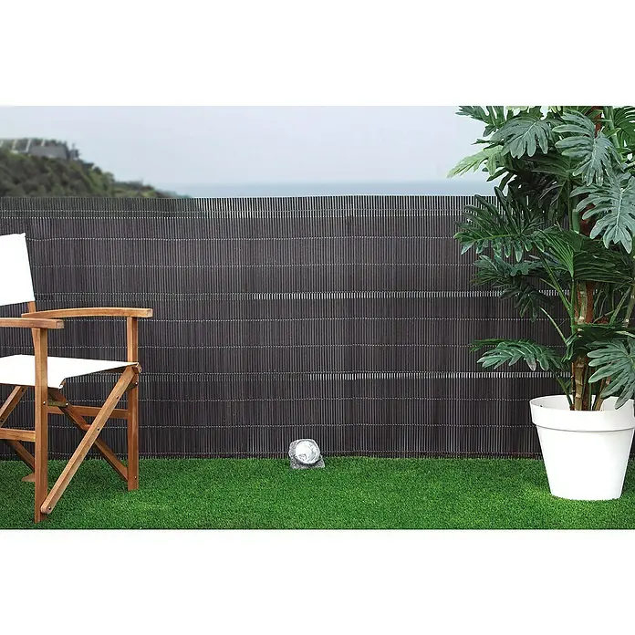 Nortene Sichtschutz LOP - Anthrazit, L x H: 300 x 150 cm - Ein stilvoller Außenbereich mit einem Sichtschutzzaun, einem Holzstuhl und einer üppigen Zimmerpflanze im weißen Topf.