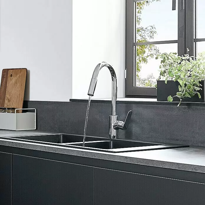 Hansgrohe Spültischarmatur Focus M41 - Chrom, Glänzend - Chrom Küchenarmatur mit fließendem Wasser in eine schwarze Doppelspüle, in einer modernen dunkelgrauen Küche.