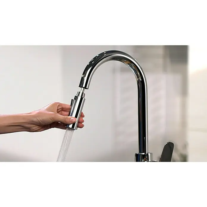 Hansgrohe Spültischarmatur Focus M41 - Chrom, Glänzend - Nahaufnahme einer Hand, die eine Küchenarmatur mit Ausziehbrause bedient, aus der Wasser fließt, vor hellem Hintergrund.