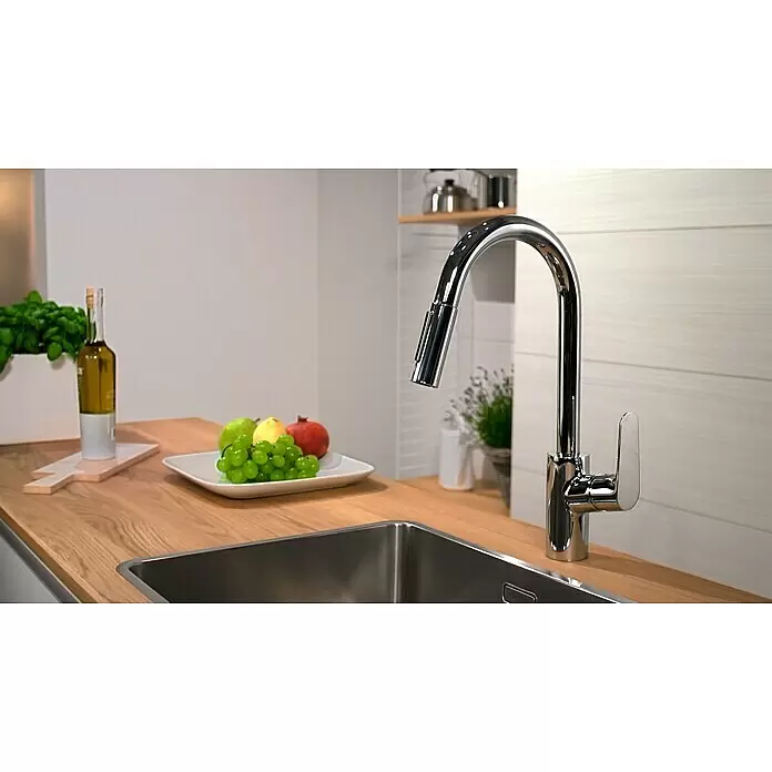 Hansgrohe Spültischarmatur Focus M41 - Chrom, Glänzend - Chrom Küchenarmatur mit Ausziehbrause, über einer Edelstahlspüle auf einer Holzplatte installiert.