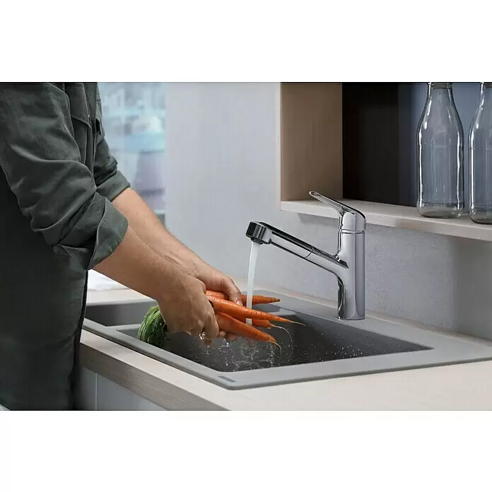 Hansgrohe Focus M41 Spültischarmatur Focus M42 - Chrom, Glänzend - Eine Person wäscht Karotten in einer grauen Spüle mit einem Chrom-Wasserhahn und fließendem Wasser.