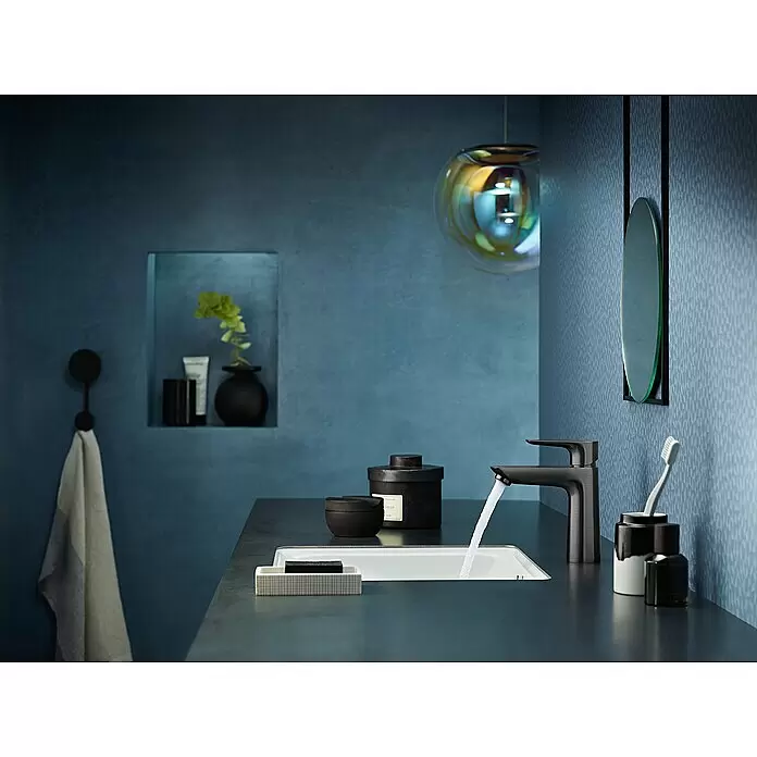 Hansgrohe Talis E Waschtischarmatur 110 - Schwarz, Matt - Mattschwarze Armatur, die Wasser in ein modernes, integriertes Waschbecken auf einer dunklen Arbeitsplatte in einem stilvollen Bad spendet.