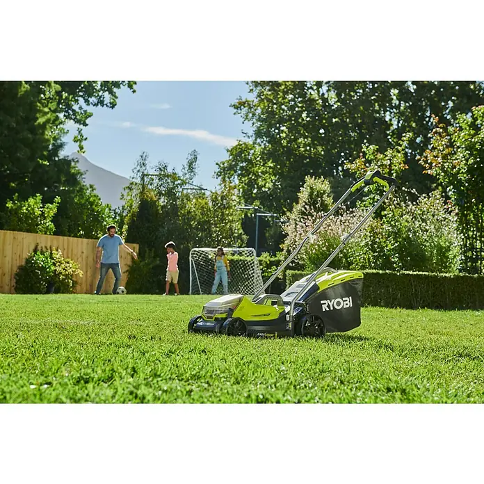 Ryobi ONE+ Akku-Rasenmäher-Set Kombo-Kit RLM1833BLT1825M mit Akku-Rasentrimmer - 1 Akku, 4 Ah - Ein RYOBI Rasenmäher steht auf einem Rasen, während eine Familie im Hintergrund Fußball spielt.