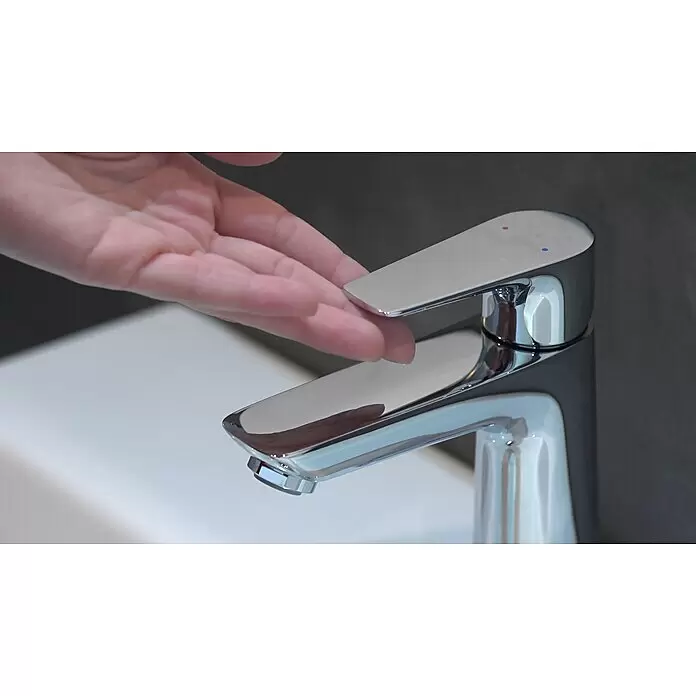 Hansgrohe Talis E Waschtischarmatur 110 - Chrom, Glänzend - Chrom-Einhebelarmatur wird von einer Hand über einem weißen Waschbecken bedient. Mit Warm- und Kaltwasseranzeige.