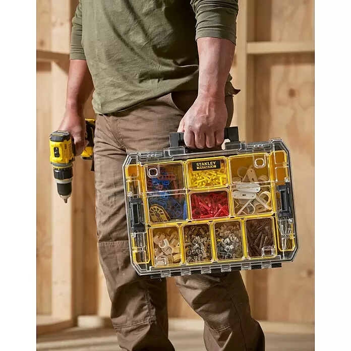 Stanley FatMax Kleinteilekoffer PRO-STACK™ - B x T x H: 337 x 440 x 119 mm, Anzahl Fächer: 10 Stk. - Eine Person trägt einen transparenten Stanley Fatmax Organizer mit gelben Fächern voller Befestigungselemente und einen gelb-schwarzen Bohrer.