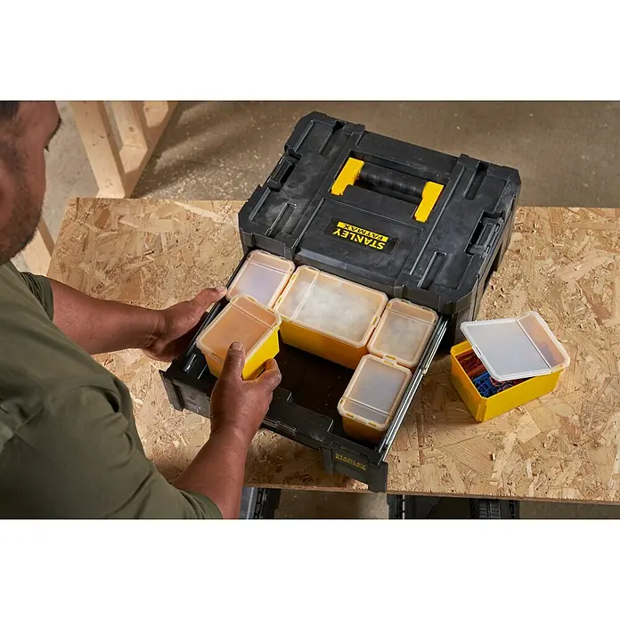 Stanley TSTAK Caja para herramientas Con cajones - 31,5 x 42,5 x 17,6 cm - Caja de herramientas Stanley Fatmax con cajones e insertos amarillos sobre una superficie de trabajo.