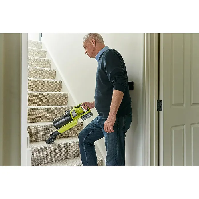 Ryobi ONE+HP Akku-Staubsauger RSV18X-1X40G - 18 V, 1 Akku, 4 Ah, Behältervolumen: 0,8 l - Ein Mann, der die Treppe mit einem gelben Akku-Staubsauger der Marke Ryobi reinigt. Der Ryobi Staubsauger ist leicht und einfach zu bedienen.