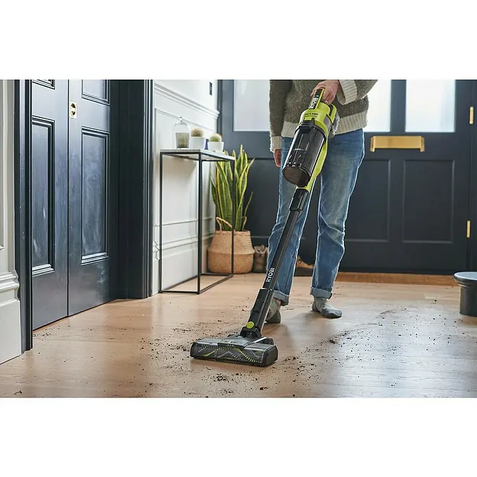 Ryobi ONE+HP Akku-Staubsauger RSV18X-1X40G - 18 V, 1 Akku, 4 Ah, Behältervolumen: 0,8 l - Eine Person verwendet einen kabellosen Ryobi-Staubsauger, um Schmutz von einem Hartholzboden zu entfernen, wobei der Fokus auf dem praktischen Design des Staubsaugers liegt.