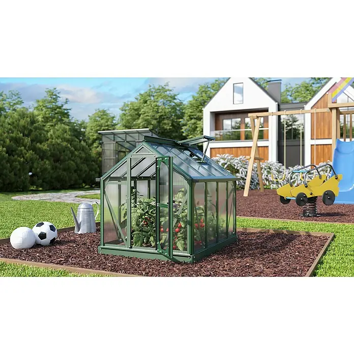 Vitavia Gewächshaus Merlin - Außenmaß inkl. Dachüberstand (B x T): 87,2 x 111,6 cm, Material Seitenwand: Kunststoff, 4 mm, Smaragd - Gewächshaus mit geöffneter Tür voller Tomatenpflanzen. Im Hintergrund ein Haus mit Spielplatz bei sonnigem Wetter.