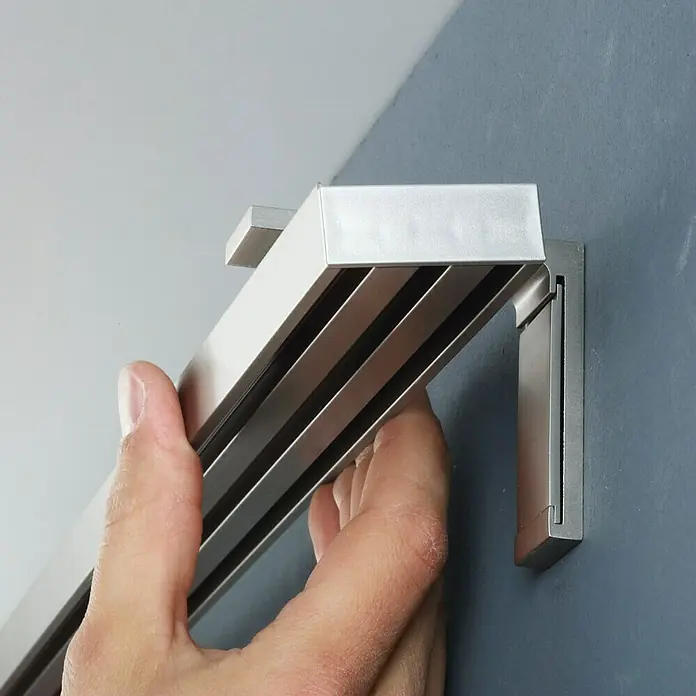 Expo Ambiente Gardinenprofil Smart Set - Anzahl Läufe: 3 Stk., Silber, 160 cm - Nahaufnahme einer Person, die eine silberne Vorhangschiene an einer Wand befestigt, die Funktionalität und elegantes Design vereint.