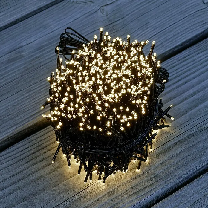 Tween Light Cadena de luces LED - Para exterior, Largo: 8,15 m, 768 ud., Funcionamiento en red, Color de luz: Blanco cálido - Un haz de luces parpadeantes con luz blanca cálida, artísticamente dispuestas sobre madera oscura, creando un ambiente acogedor.